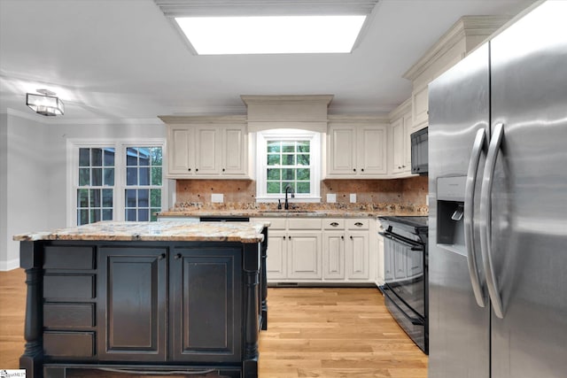 kitchen with black appliances, light wood-style flooring, a sink, white cabinetry, and crown molding