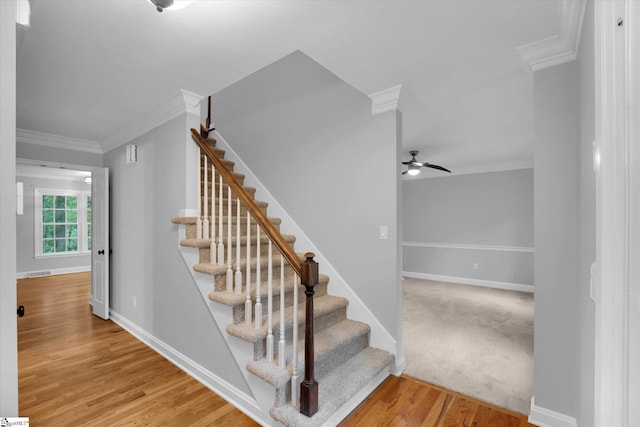 staircase with ornamental molding, baseboards, ceiling fan, and wood finished floors