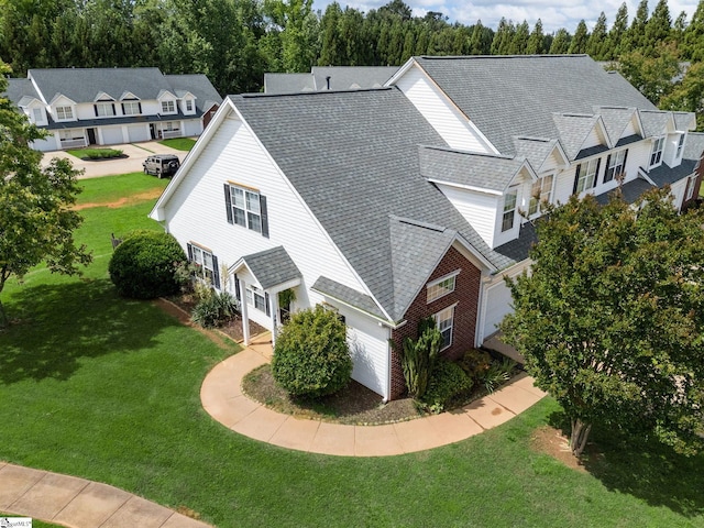view of side of property featuring a yard, roof with shingles, and brick siding