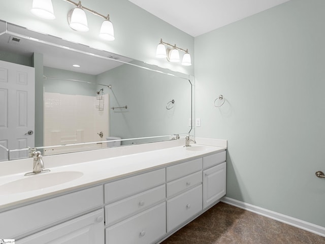 bathroom featuring baseboards, double vanity, and concrete floors