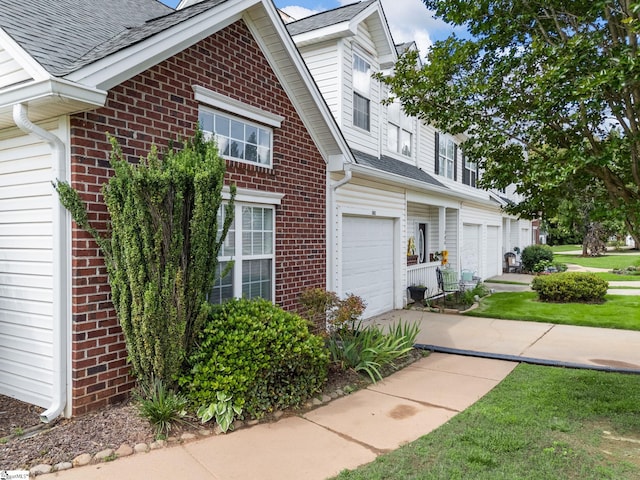 view of property exterior featuring an attached garage, brick siding, roof with shingles, concrete driveway, and a lawn