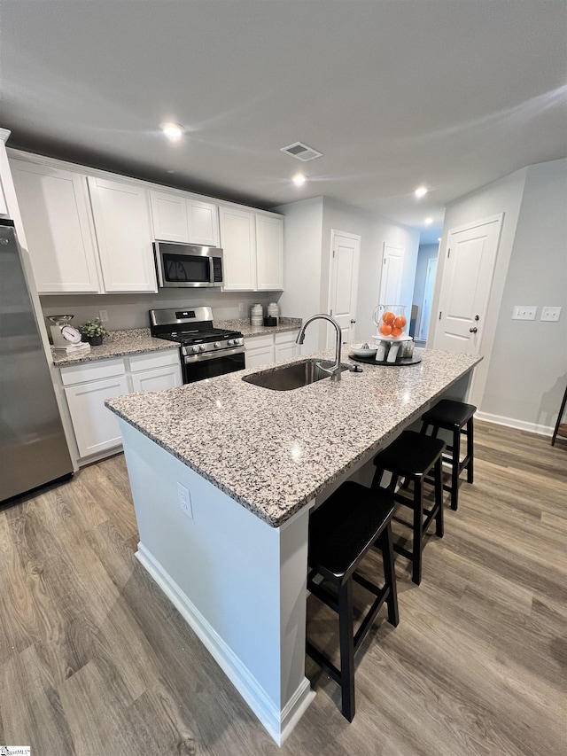1222 Forestbrook Ln, Spartanburg, SC 29303 - kitchen with appliances with stainless steel finishes, light wood-style floors, a sink, white cabinets, and a kitchen bar