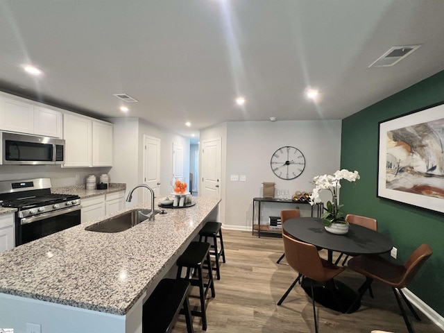 1222 Forestbrook Ln, Spartanburg, SC 29303 - kitchen featuring stainless steel appliances, a sink, white cabinets, a kitchen bar, and light wood-style flooring