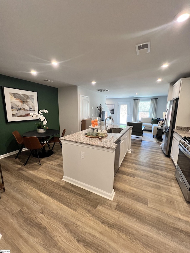 1222 Forestbrook Ln, Spartanburg, SC 29303 - kitchen with a sink, appliances with stainless steel finishes, an island with sink, white cabinetry, and light wood-style floors