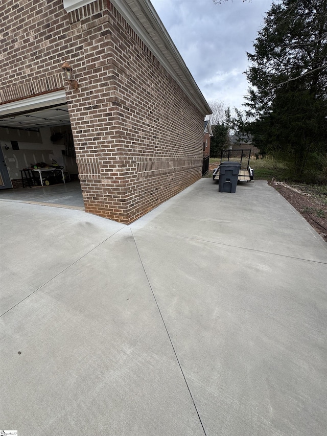 view of side of property with a patio area, a garage, and brick siding