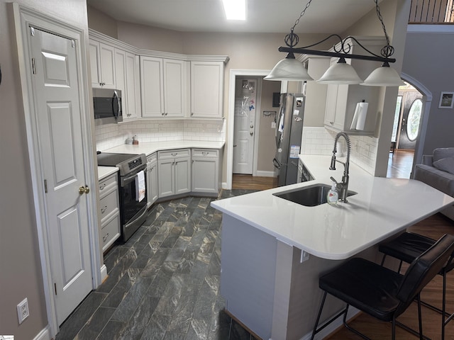 kitchen with stainless steel appliances, a sink, backsplash, a breakfast bar area, and white cabinetry