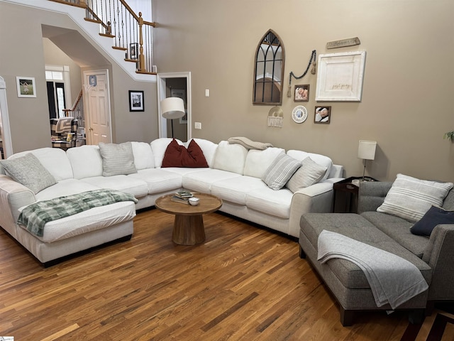 living area featuring stairs, wood finished floors, and a towering ceiling