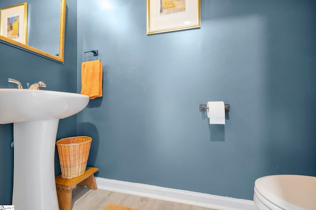 bathroom with baseboards, wood finished floors, and toilet