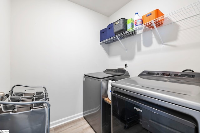laundry area featuring washing machine and dryer, light wood-style floors, and baseboards