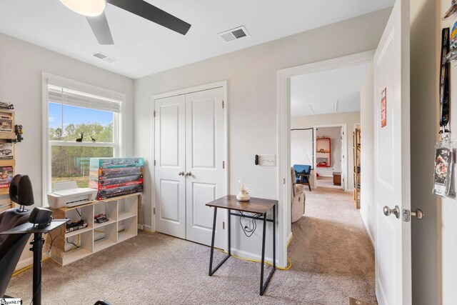 carpeted office with a ceiling fan