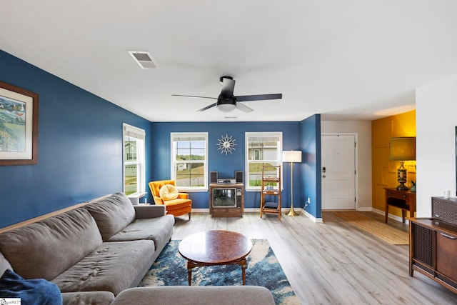 living room featuring light wood-style flooring, a ceiling fan, and baseboards