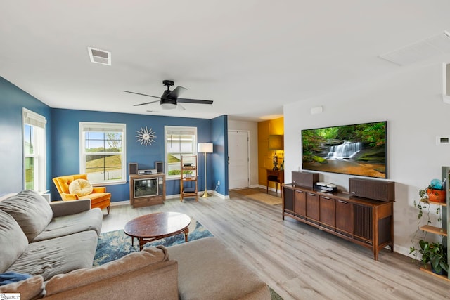 living room featuring light wood-style flooring, baseboards, and a ceiling fan