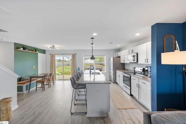 kitchen with appliances with stainless steel finishes, a sink, light wood-style flooring, white cabinets, and recessed lighting