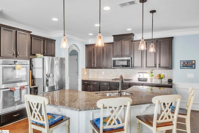 549 Allenton Way, Greer, SC 29651 - kitchen featuring stainless steel appliances, a sink, dark brown cabinetry, crown molding, and arched walkways