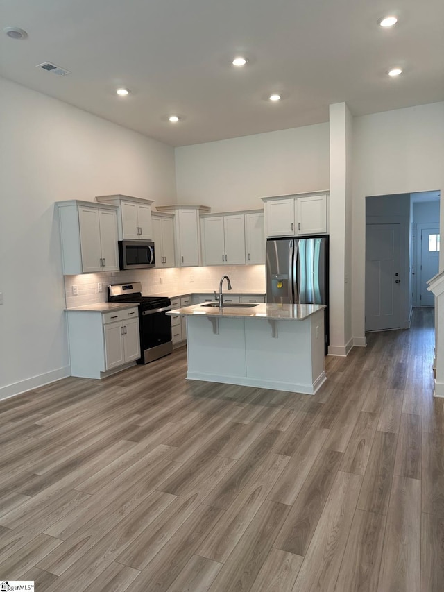 234 Woodhouse Way # 1, Greenville, SC 29605 - kitchen featuring appliances with stainless steel finishes, a sink, light wood-style floors, tasteful backsplash, and a kitchen breakfast bar