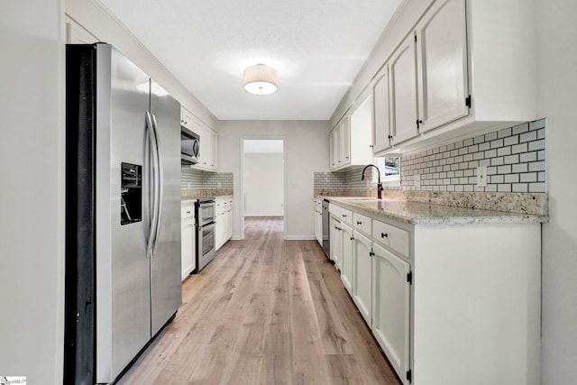 167 Lake Bowen Dr, Inman, SC 29349 - kitchen with stainless steel appliances, tasteful backsplash, light wood-type flooring, white cabinets, and a sink