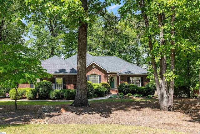 ranch-style house featuring brick siding and roof with shingles