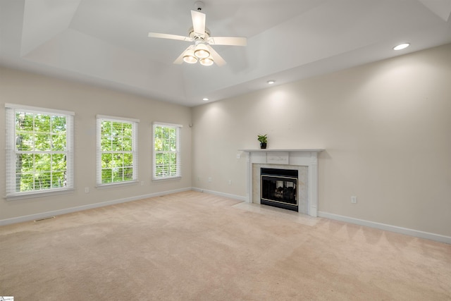 unfurnished living room featuring healthy amount of natural light, light carpet, a tiled fireplace, baseboards, and recessed lighting