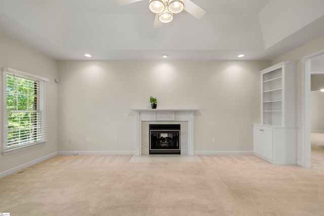 unfurnished living room with light carpet, a high end fireplace, recessed lighting, ceiling fan, and baseboards