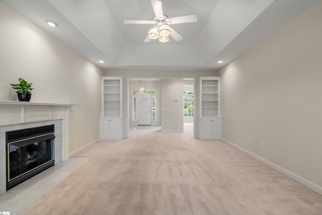 unfurnished living room with ceiling fan, a premium fireplace, baseboards, light colored carpet, and recessed lighting