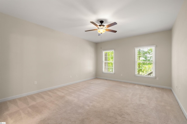 unfurnished room with light colored carpet, baseboards, and ceiling fan