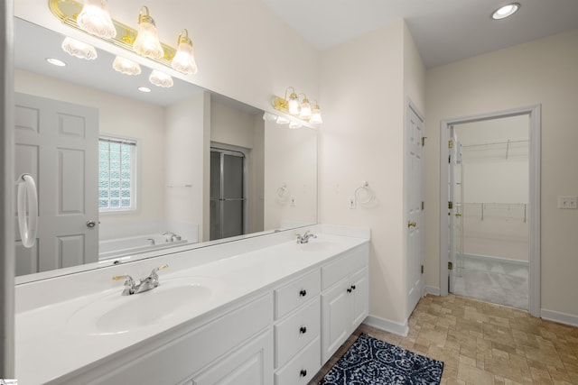 full bathroom featuring baseboards, recessed lighting, a garden tub, double vanity, and stone finish flooring