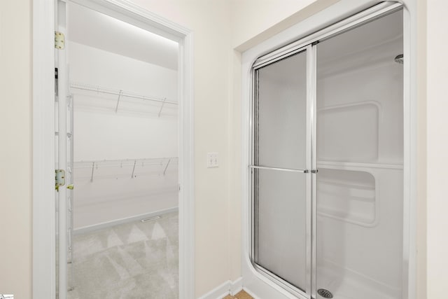 full bath featuring a shower stall, a spacious closet, and baseboards
