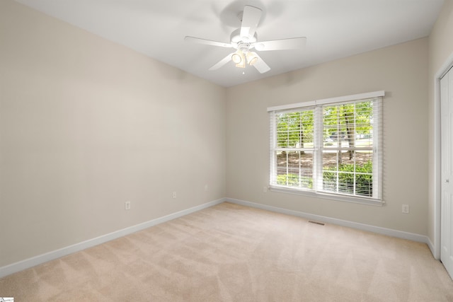 spare room with light carpet, baseboards, and a ceiling fan