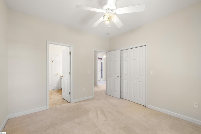 unfurnished bedroom with light carpet, baseboards, a closet, and a ceiling fan