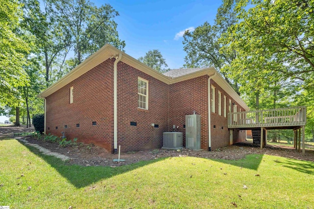 view of home's exterior featuring a deck, central AC, a lawn, and brick siding