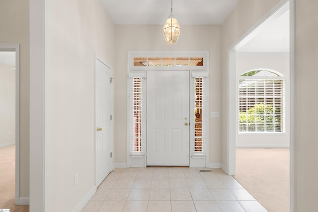 entryway featuring baseboards, light tile patterned flooring, and light carpet