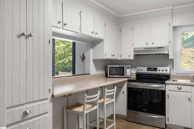 65 Westview Ave, Greenville, SC 29607 - kitchen with stainless steel appliances, under cabinet range hood, crown molding, light countertops, and white cabinets
