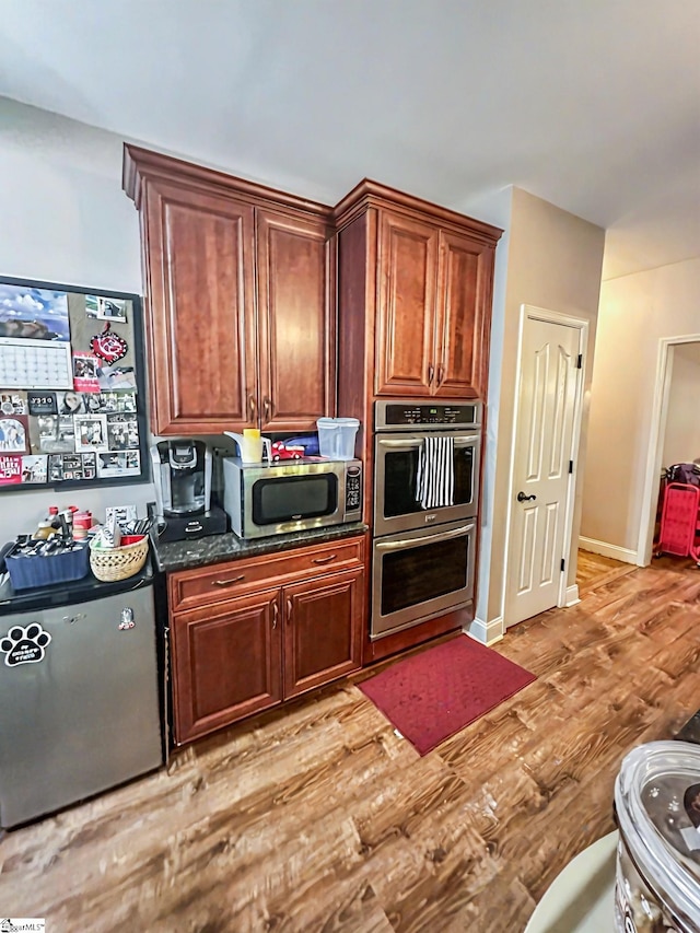 586 Silver Shoals Cir, Marietta, SC 29661 - kitchen featuring appliances with stainless steel finishes, light wood finished floors, dark stone counters, and baseboards