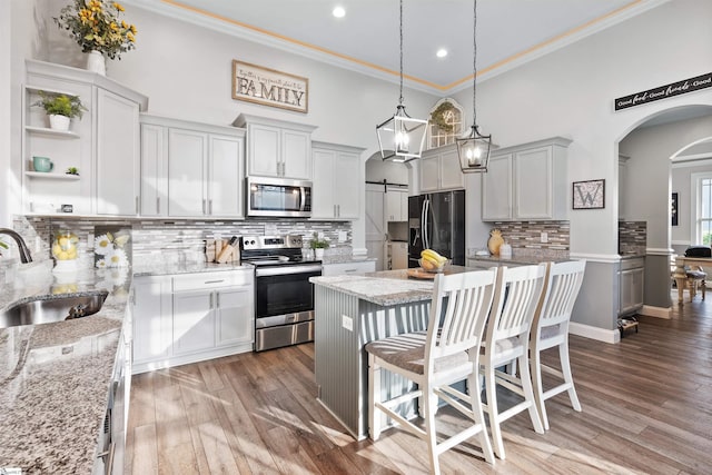 406 Jersey Queen Trl, Greer, SC 29651 - kitchen with appliances with stainless steel finishes, a sink, arched walkways, crown molding, and a kitchen island