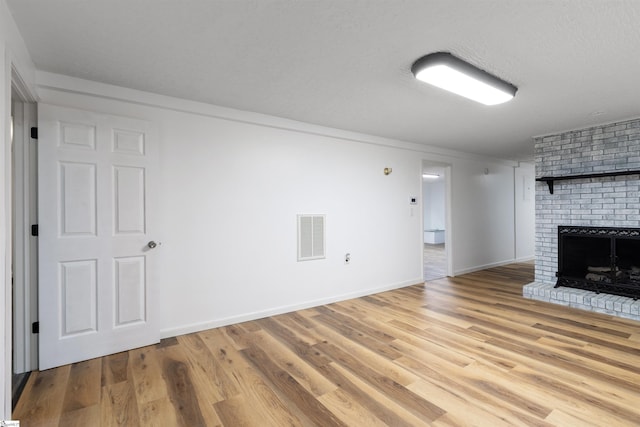 12 Fowler Cir, Greenville, SC 29607 - unfurnished living room featuring a brick fireplace, light wood-style flooring, baseboards, and a textured ceiling