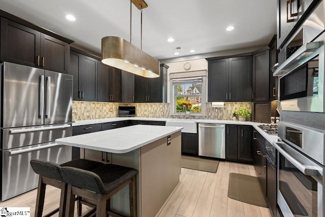 5 Maxfli Ct, Greenville, SC 29690 - kitchen with stainless steel appliances, a sink, a center island, light countertops, and light wood-type flooring