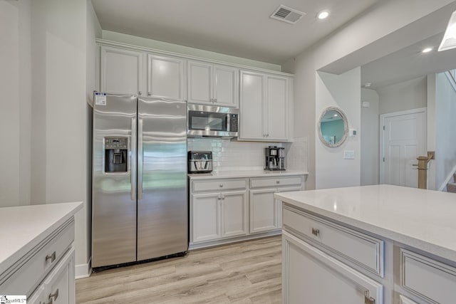1128 Grovewood Ct, Moore, SC 29369 - kitchen with appliances with stainless steel finishes, light countertops, light wood-type flooring, tasteful backsplash, and white cabinets