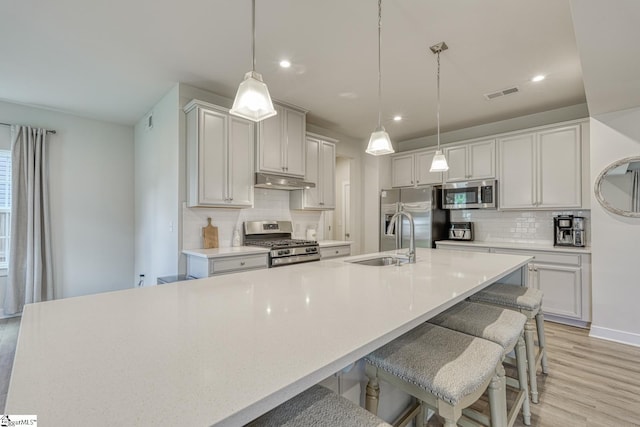 1128 Grovewood Ct, Moore, SC 29369 - kitchen with stainless steel appliances, a sink, backsplash, light wood-type flooring, and under cabinet range hood