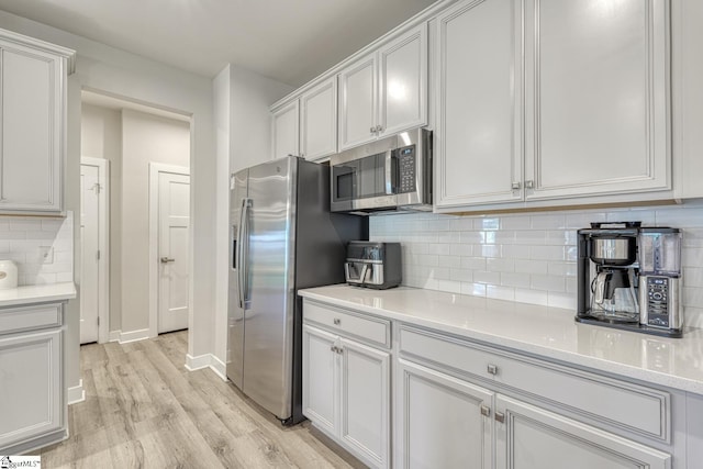1128 Grovewood Ct, Moore, SC 29369 - kitchen featuring appliances with stainless steel finishes, light wood finished floors, backsplash, light countertops, and white cabinets