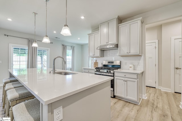 1128 Grovewood Ct, Moore, SC 29369 - kitchen featuring stainless steel gas range, a sink, under cabinet range hood, light wood-style flooring, and tasteful backsplash