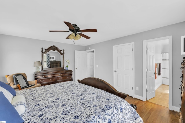 bedroom with wood finished floors, baseboards, a ceiling fan, and ensuite bathroom