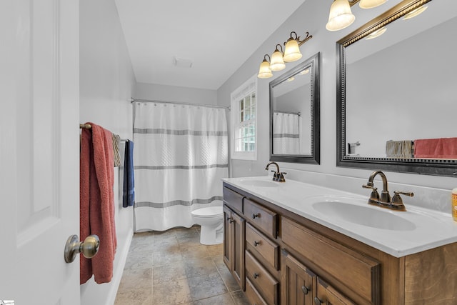 full bath featuring double vanity, toilet, stone finish flooring, baseboards, and curtained shower