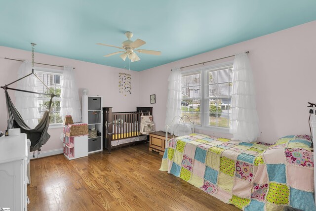 bedroom with multiple windows, wood finished floors, and a ceiling fan