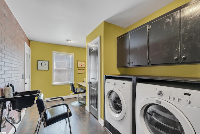 laundry area featuring cabinet space, washing machine and dryer, brick wall, dark wood-style flooring, and baseboards
