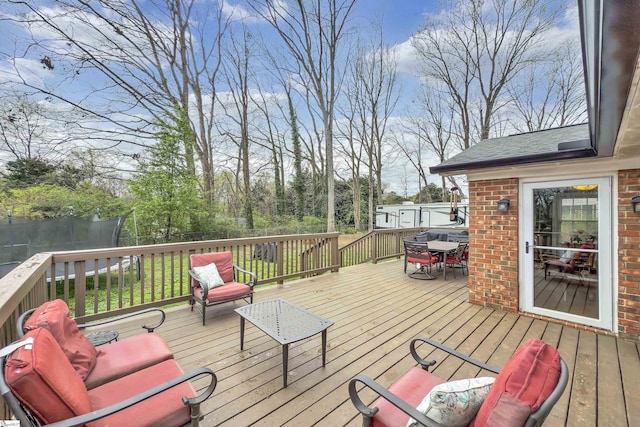 wooden deck with outdoor dining space and a trampoline