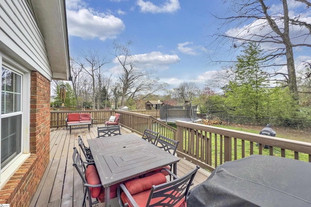 deck featuring a trampoline, a fenced backyard, and outdoor dining space