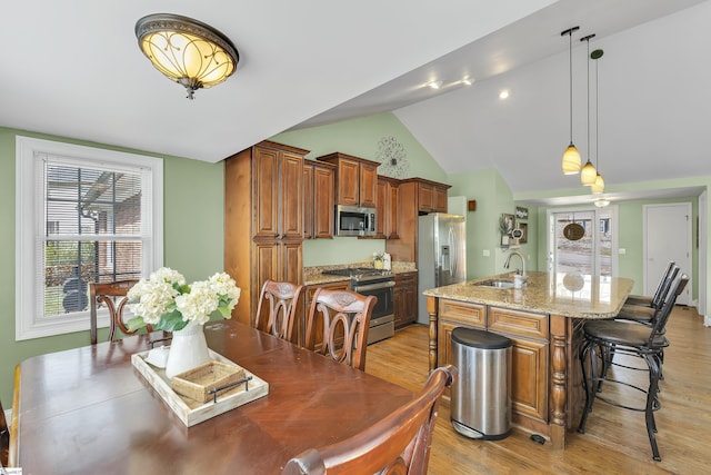 dining space featuring light wood-type flooring and vaulted ceiling