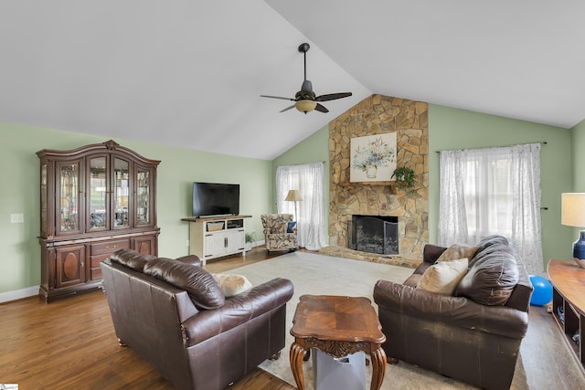 living area with a ceiling fan, vaulted ceiling, wood finished floors, a fireplace, and baseboards
