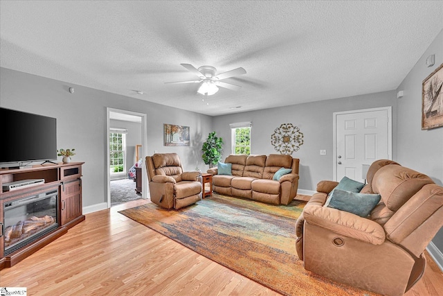 205 Willow Leaf Dr, Seneca, SC 29672 - living room featuring light wood-style flooring, ceiling fan, a textured ceiling, baseboards, and a glass covered fireplace