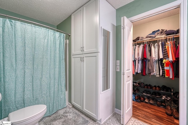 103 Cheyenne Ridge Rd, Campobello, SC 29322 - bathroom with a textured ceiling, toilet, a walk in closet, wood finished floors, and a shower with curtain